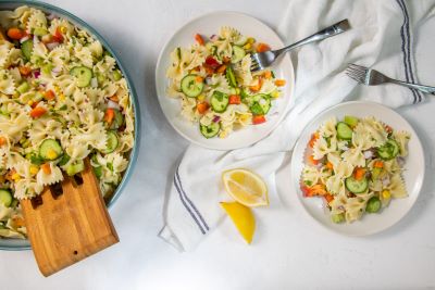 Farfalle pasta salad in a large bowl and on two small plates