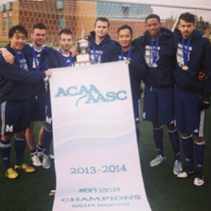 Tyler Simmons standing beside the ACAA Men's Soccer trophy MSVU won in 2013-2014