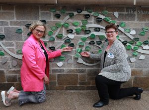 Penelope Joy Henneberry pointing to her left on the Women's Wall of honour