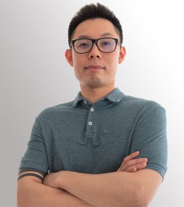 Dr Michael Lin, posing for the camera with his arms crossed. He is wearing glasses and a green polo.