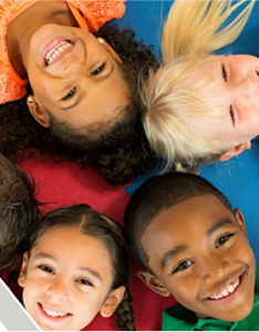 A group of four children smiling for the camera while lying down on the floor in a circle