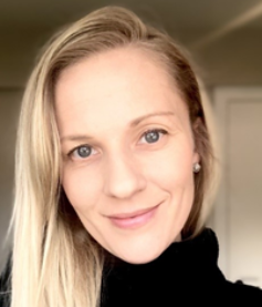 A headshot of Dr. Andrea Fraser. She is wearing a black turtleneck and has long blonde hair swept onto one side