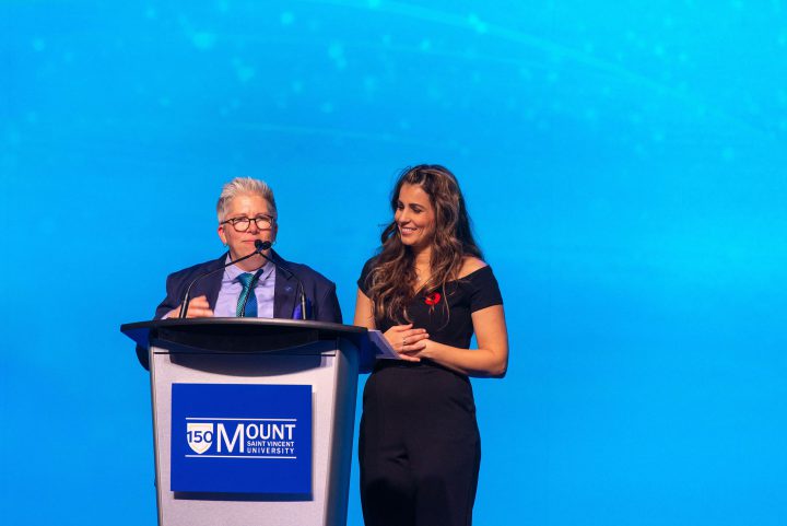 Joël Dickinson and Ana Almeida speaking at the podium to the attendees