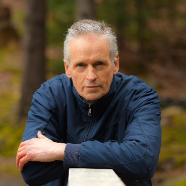 Sports photographer Dave Gallant leaning against a fence posing for a photo