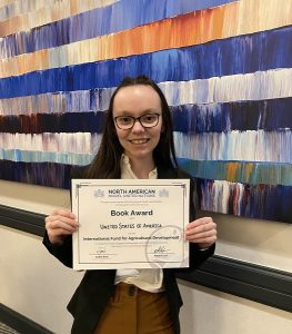 Morgan Hussey holding book award for her position paper