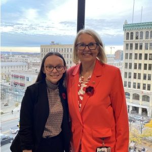 Morgan Hussey and Senator Jane Cordy, standing in front of a glass window