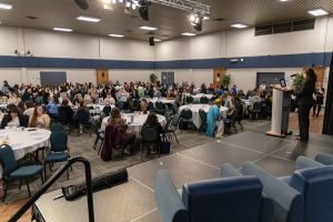 The audience seated around tables at the Girls Conference 2025