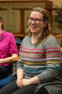 Paige Drake sitting down in a striped sweater