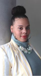 Rajean Willis posing for a headshot wearing a white jacket and a teal turtleneck