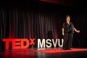 Rajean Willis giving a speech in front of the TED x MSVU sign 