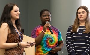 Natasha Perfect, Ava Lyon, Skairy Vincent, Mackenzie Richard and Mwapé Kasongo, holding a microphone while receiving their first place prize