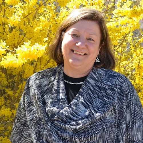 Janice Keefe, standing outside near a yellow maple tree