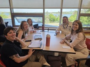 Several attendees sitting around a table at the Nova Scotia Developers event, looking and smiling at the camera