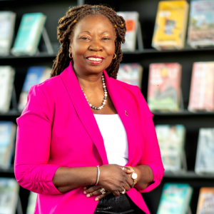 Ann Divine, wearing a pink blazer and smiling at the camera