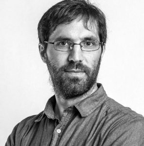 Dr. Eric Oliver, in a greyscale photo wearing a polo and glasses