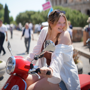 Katie Bates in a red moped in the street, wearing a white blazer and smiling away from the camera