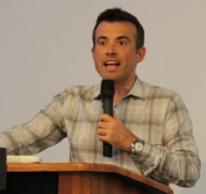 Spiros Papageorgiou, speaking to the audience at a podium