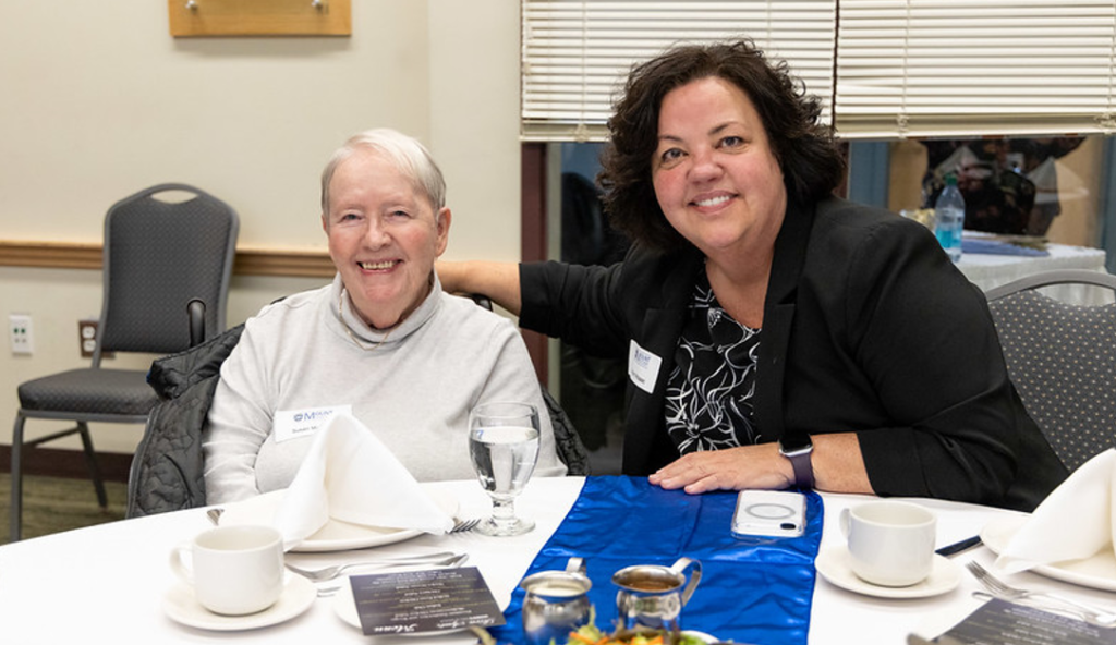Susan and Robyn McIsaac, standing sitting down at a table
