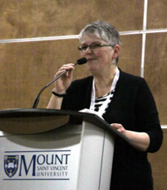 Dr. Katherine Darvesh, speaking at a podium with the MSVU logo on the podium