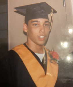 Martin Morrison, wearing his convocation attire at his first convocation ceremony. With a yellow cloak and a red flower