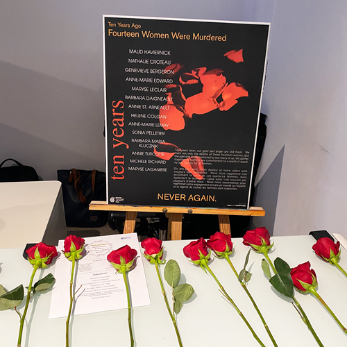 Roses placed in front of a sign for the National Day of Remembrance & action on violence against women