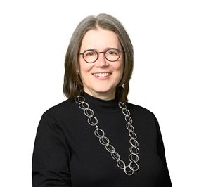 Patricia (Patti) Towler, wearing a black sweater and circular-rimmed red glasses
