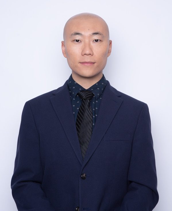 Cong Chen, wearing a blue suit and a neutral expression against a white backdrop