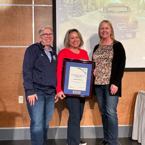 Dr. Christine McLean receiving an award. On her left is Dr. Joël Dickinson and on her right is Kim Peitzsche.