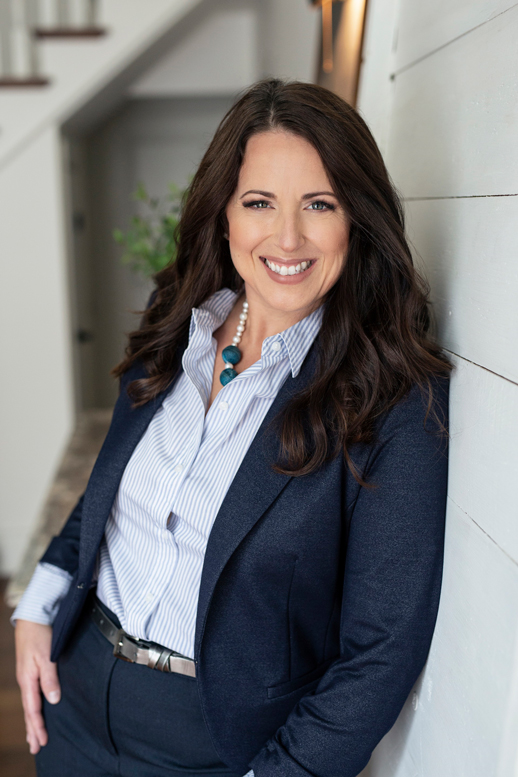 Heather Strickey, wearing a navy suit and a light blue blouse, smiling at the camera