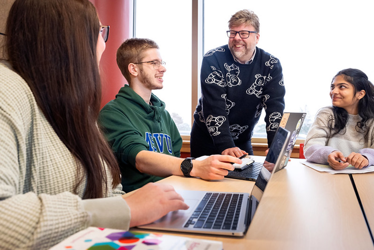 Dr Phillip Joy talking with 3 students in a McCain classroom during a lecture