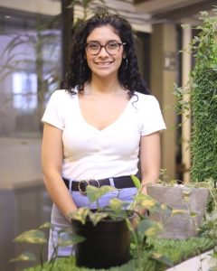 Sara Mafla standing in front of some plants and smiling at the camera.