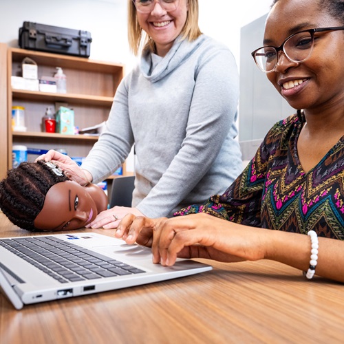 Dr Christine Lackner and a research assistant working over a laptop with a model of a head
