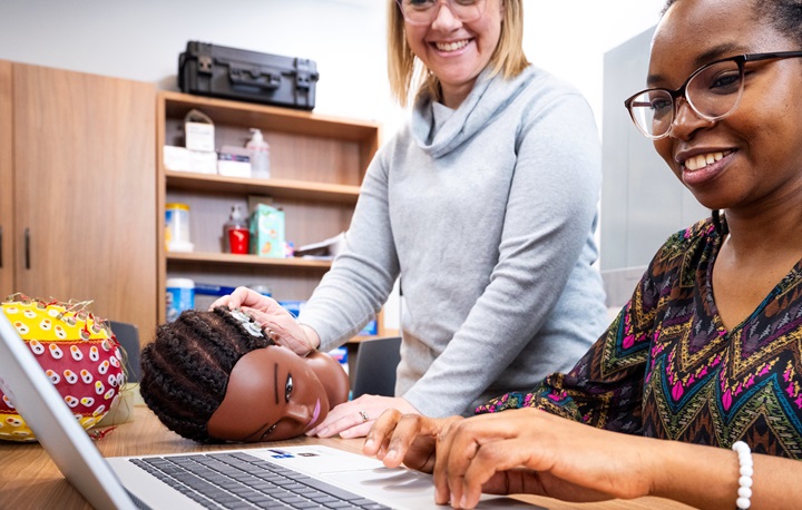 Dr Christine Lackner and a research assistant working over a laptop with a model of a head