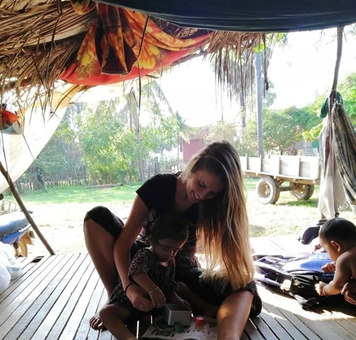 Jelisa Gallant, sitting on wooden planks and playing with a small child