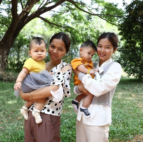 Two of the research partners for Kyly Whitfield, holding 2 small children