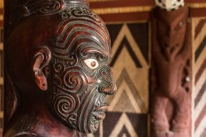 A Māori wood carving against a wooden wall