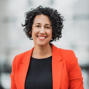 Claudia Chender, wearing an orange jacket and a black shirt