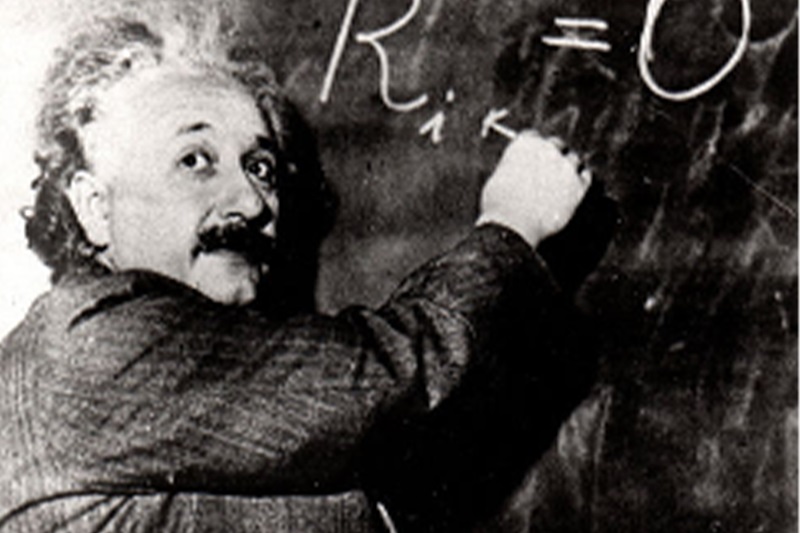 Albert Einstein writing on a blackboard