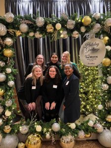 Suwela and several students posing behind a floral frame