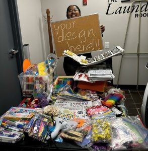 Suwela holding several craft supplies and paints