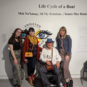 Cheyenne Hardy and Shannan Grant, posing beside two Mi'kmaw artists, Alan Syliboy and Grace Berry in front of the "Life Cycle of a Boat exhibit"
