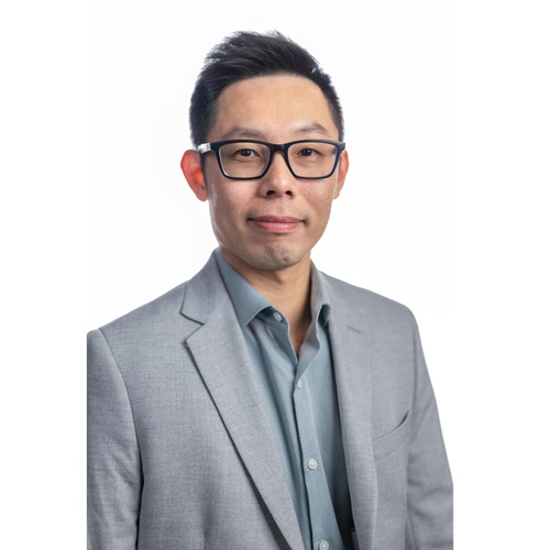 Dr. Michael Pin-Chuan Lin, wearing a grey blazer and a steel blue shirt, smiling at the camera