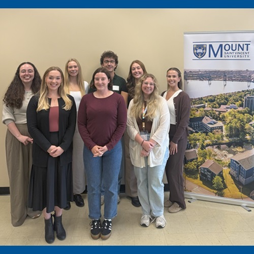 Several students from the inaugural Doctor of Psychology (PsyD) Class, posing for a photo beside a MSVU banner