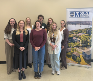 Several students from the inaugural Doctor of Psychology (PsyD) Class, posing for a photo beside a MSVU banner