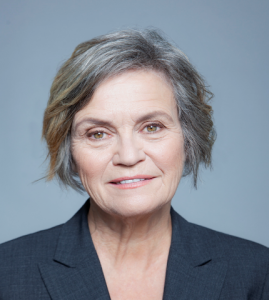 Jane Bertrand, wearing a gray suit jacket, smiling at the camera