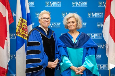 Dr Joel Dickinson and Dr Jane Bertrand posing for a photo in the Robing Room against a MSVU backdrop