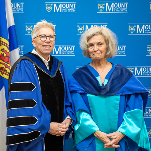 Dr Joel Dickinson and Dr Jane Bertrand posing for a photo in the Robing Room against a MSVU backdrop.