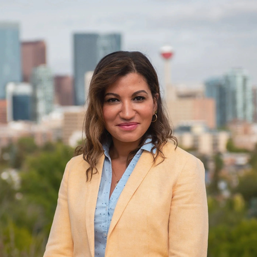 Dr. Maki Motapanyane, wearing a yellow suit jacket standing in front of a cityscape