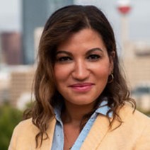 Dr. Maki Motapanyane, wearing a yellow suit jacket standing in front of a cityscape